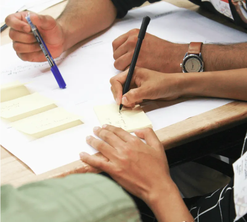 Hands writing on sticky notes during a design workshop